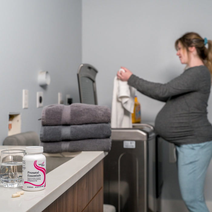 A pregnant woman doing laundry behind the Prenatal Essentials